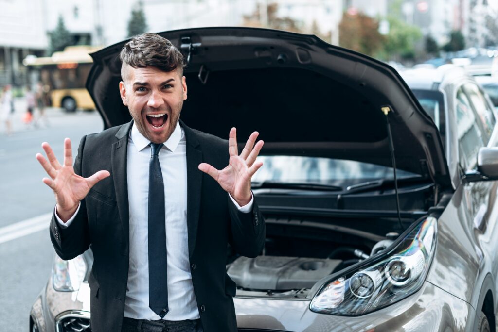 The young, handsome man is very annoyed because the car broke down