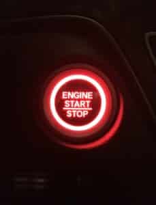 Modern automobile illuminated engine start stop ignition button in red